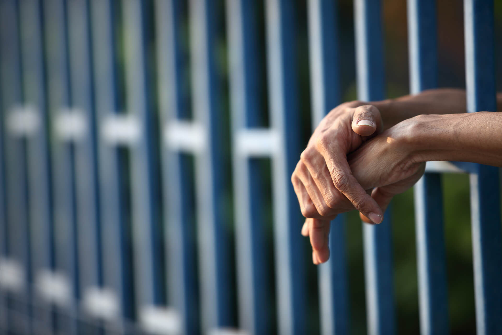 pair of hands from behind prison-bars